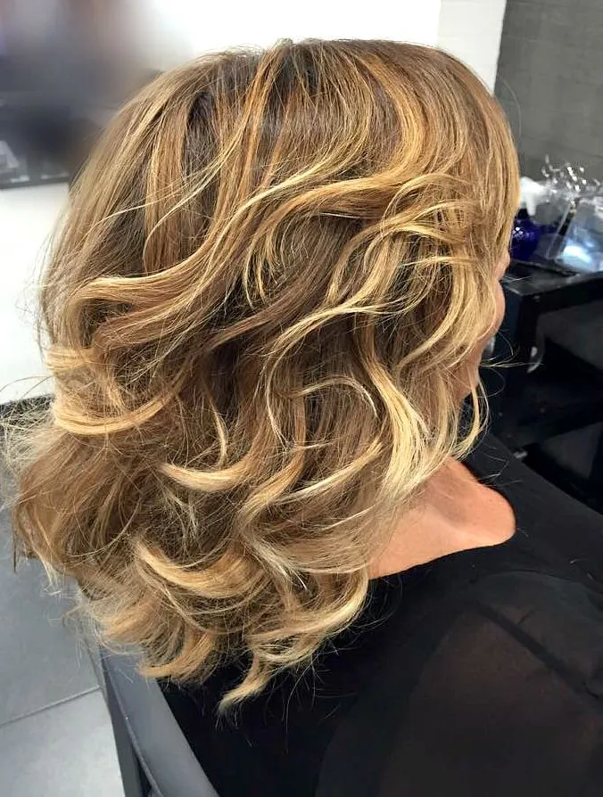 Capelli mossi con shatush biondo miele, visti di spalle in salone
